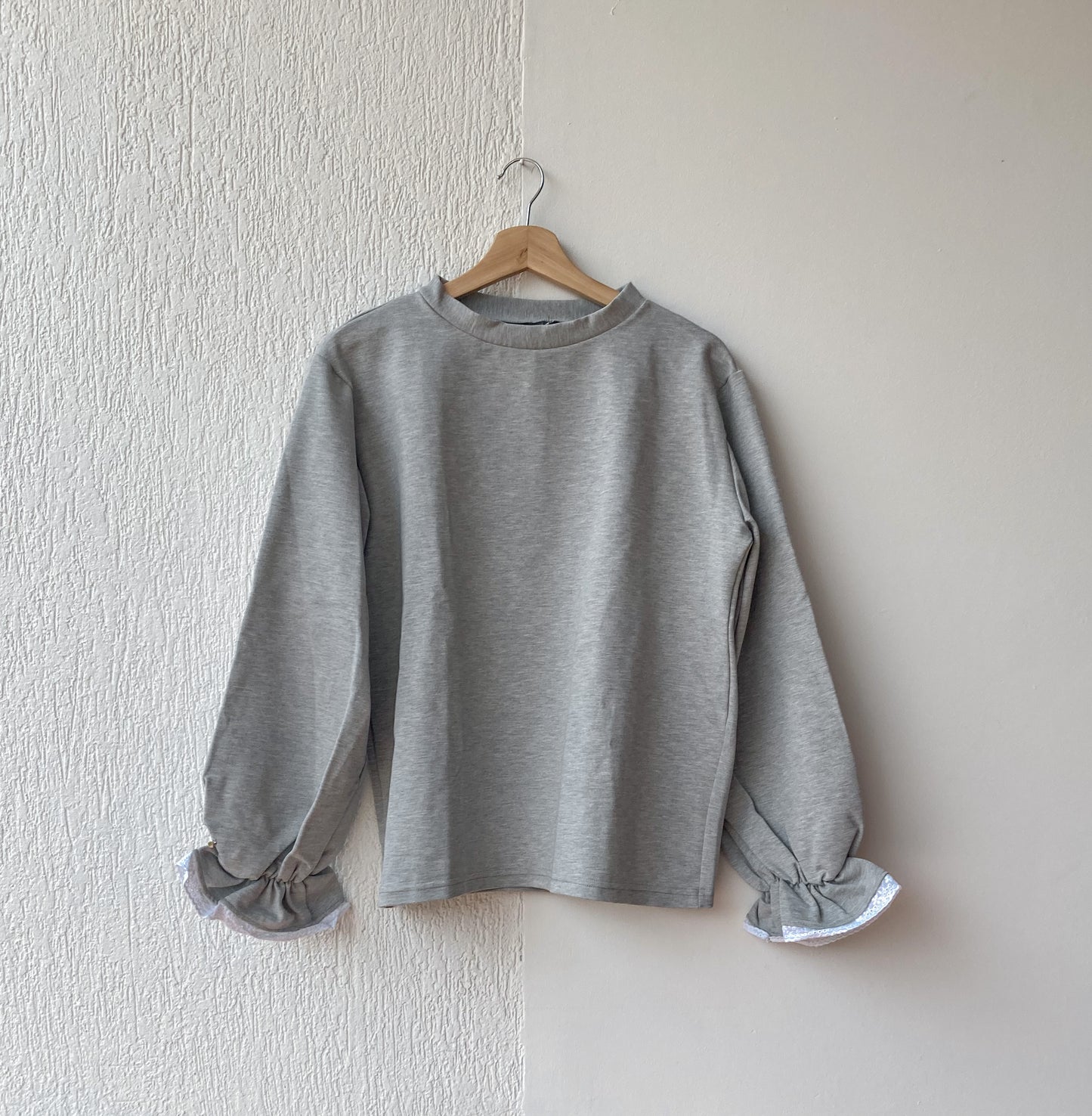 Buzo perchado gris jaspeado con detalles de encaje en el puño y bolero con resorte. angulo frontal