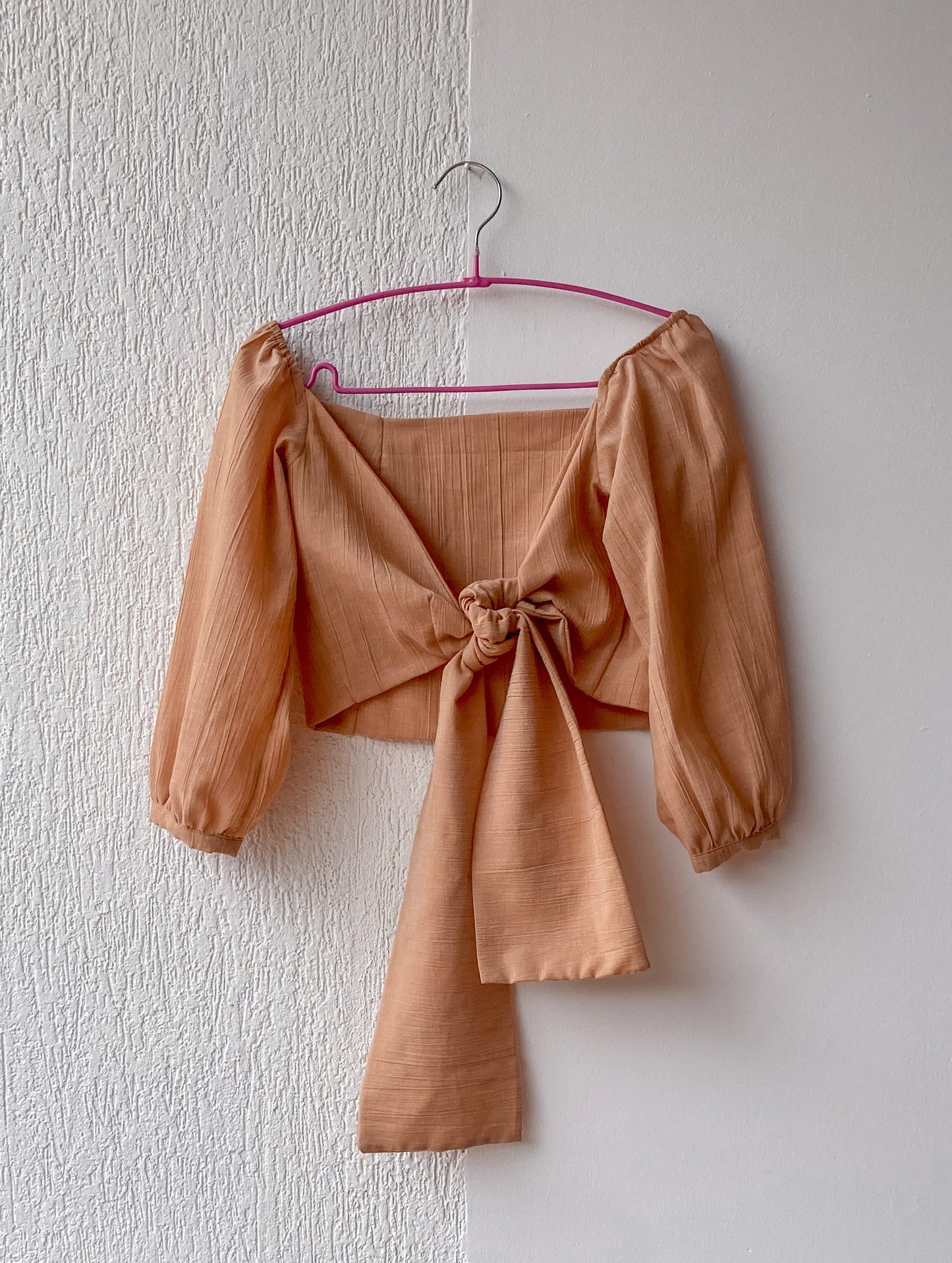 Esta blusa es un crop top que tiene un escote cuadrado y un nudo que se puede atar por delante o por detrás. Es una prenda versátil y cómoda que se adapta a diferentes estilos. 100% Colombiano, producto local.