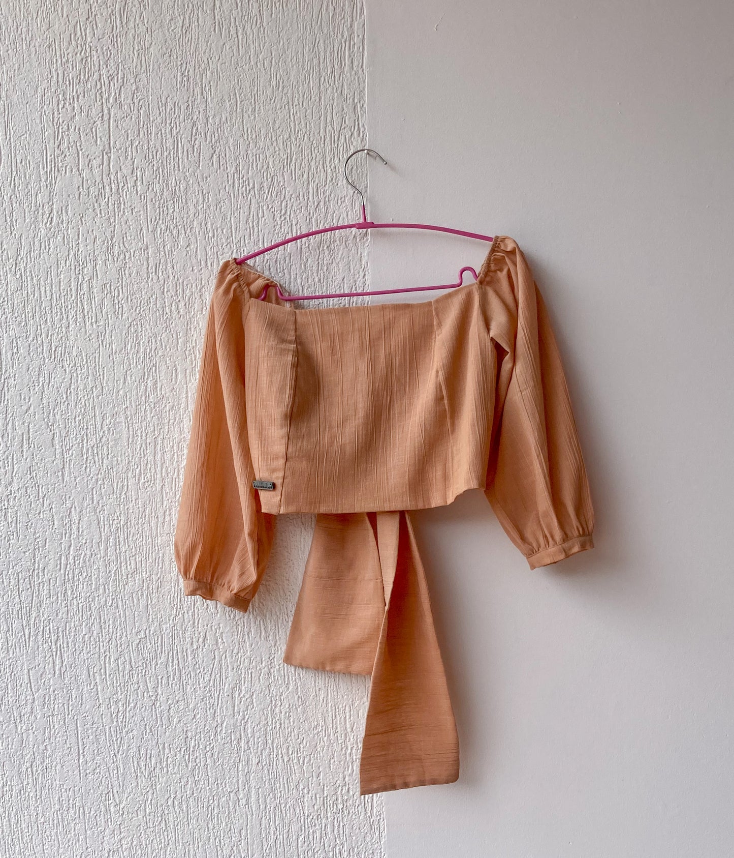 Esta blusa es un crop top que tiene un escote cuadrado y un nudo que se puede atar por delante o por detrás. Es una prenda versátil y cómoda que se adapta a diferentes estilos. 100% Colombiano, producto local.