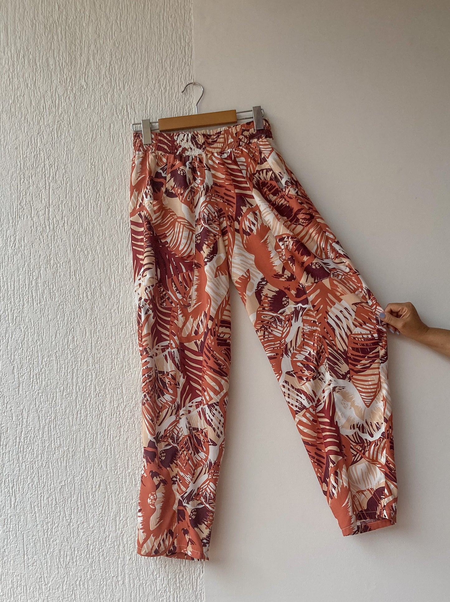 Pantalón bota recta, hecho en chalis estampado de hojas en tonos calidos, con resorte en toda la cintura y bolsillo grandes. foto de producto en fondo entero